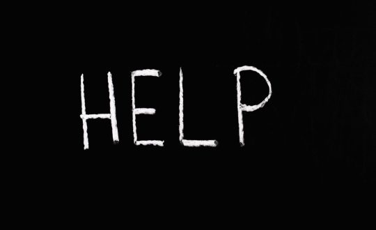 Chalk-written 'HELP' on a deep black background symbolizes assistance and encouragement.